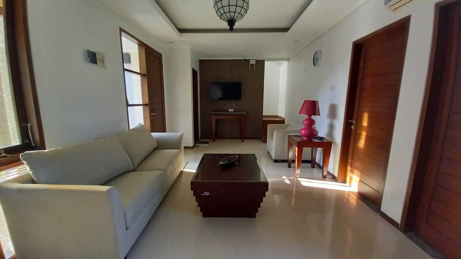 A living room with a sofa, a coffee table, a TV, and a lamp.