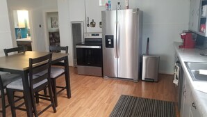A compact kitchen with a stainless steel refrigerator, a built-in oven, and a sink. - Great Bungalow in the gateway to the Black Hills (Sturgis)