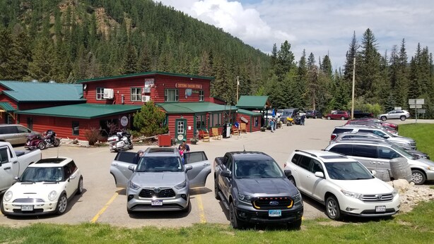 A parking lot with several cars and a building with a green roof and red walls. - Great Bungalow in the gateway to the Black Hills (Sturgis)