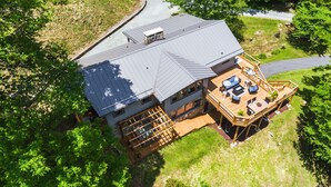 Une maison à deux étages dotée d’une terrasse couverte et d’une cheminée en pierre.