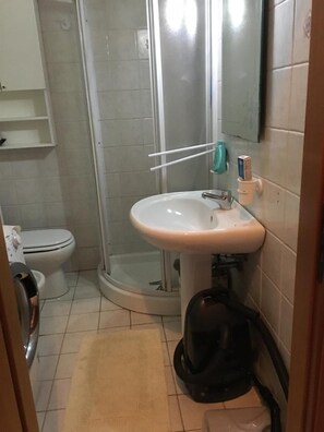 A bathroom with a white sink, a toilet, and a glass shower enclosure. - Pressi Caronte Appartmento in Messina (Messina)