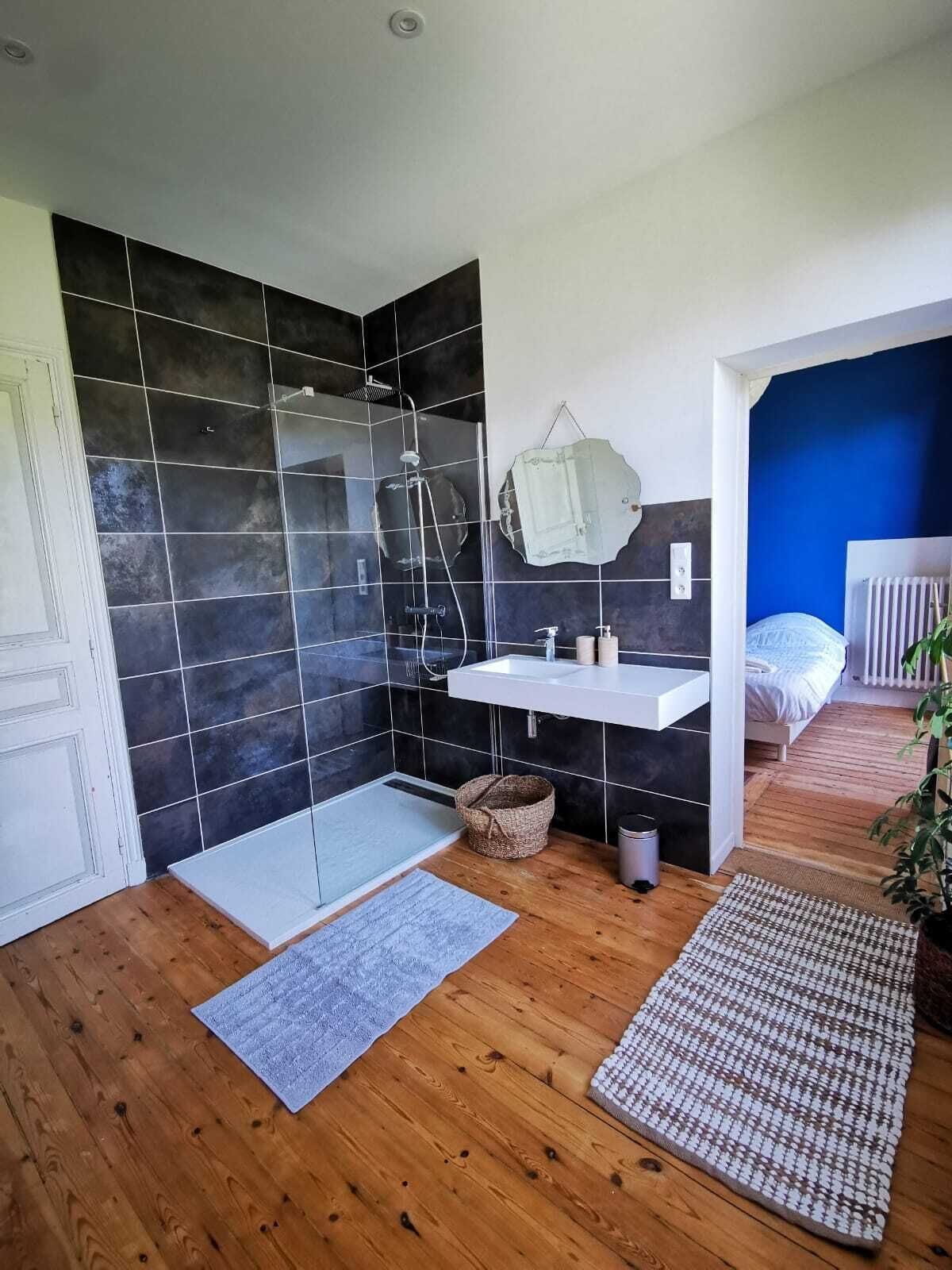 A modern bathroom with a glass shower enclosure, a white sink, and a mirror.