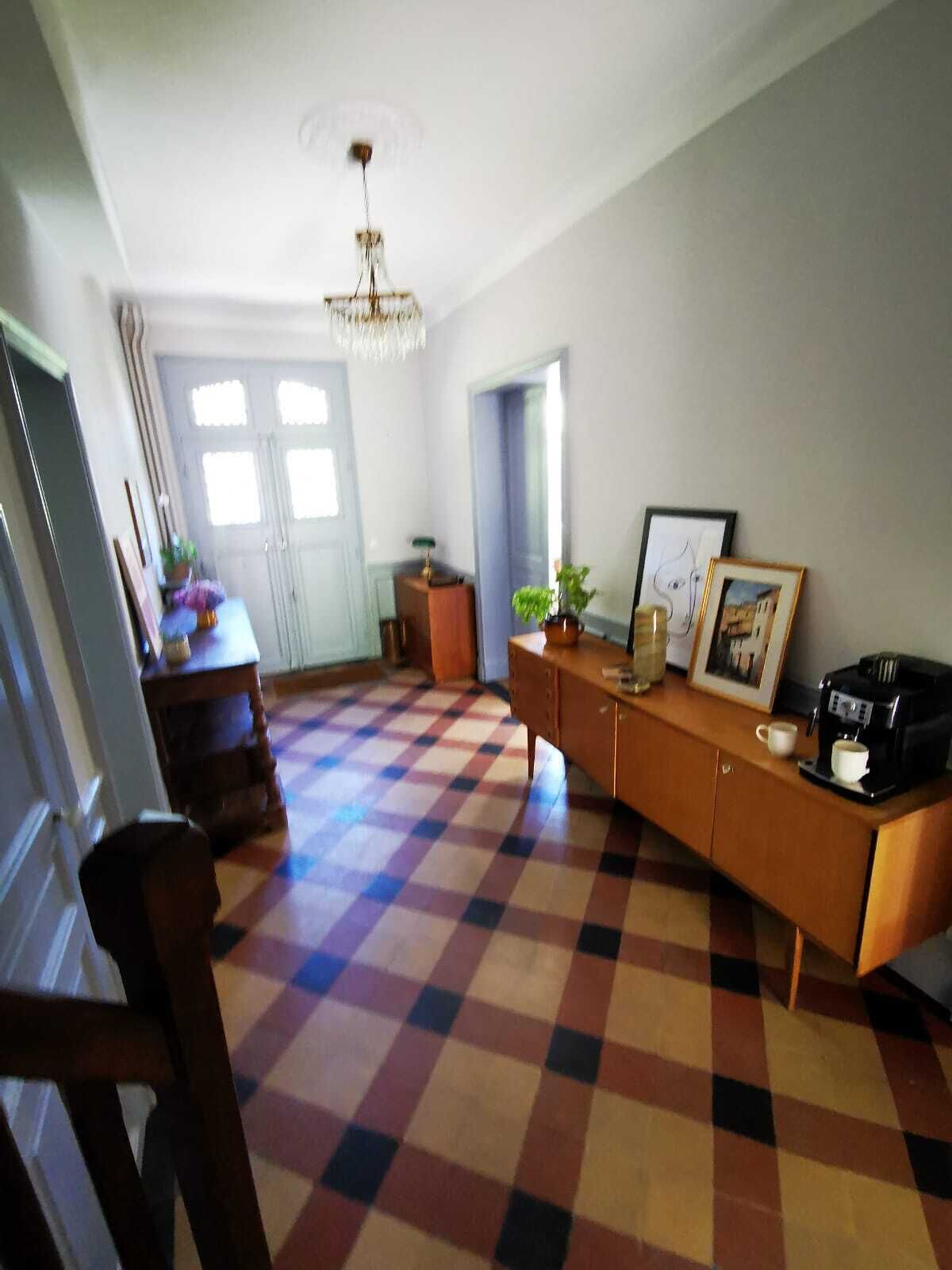 Una sala de estar con piso a cuadros, un armario de madera, una máquina de café y una araña.