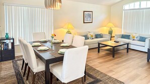 A modern living room with a dining area, featuring a sofa set, coffee table, and a dining table with chairs.