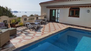 A pool area with a tiled deck, lounge chairs, and a view of the sea. - Exclusive villa with private pool and gym (Almuñécar)