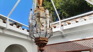 A room with a white textured wall, a large mirror with a geometric pattern, and a hanging lantern. - Exclusive villa with private pool and gym (Almuñécar)