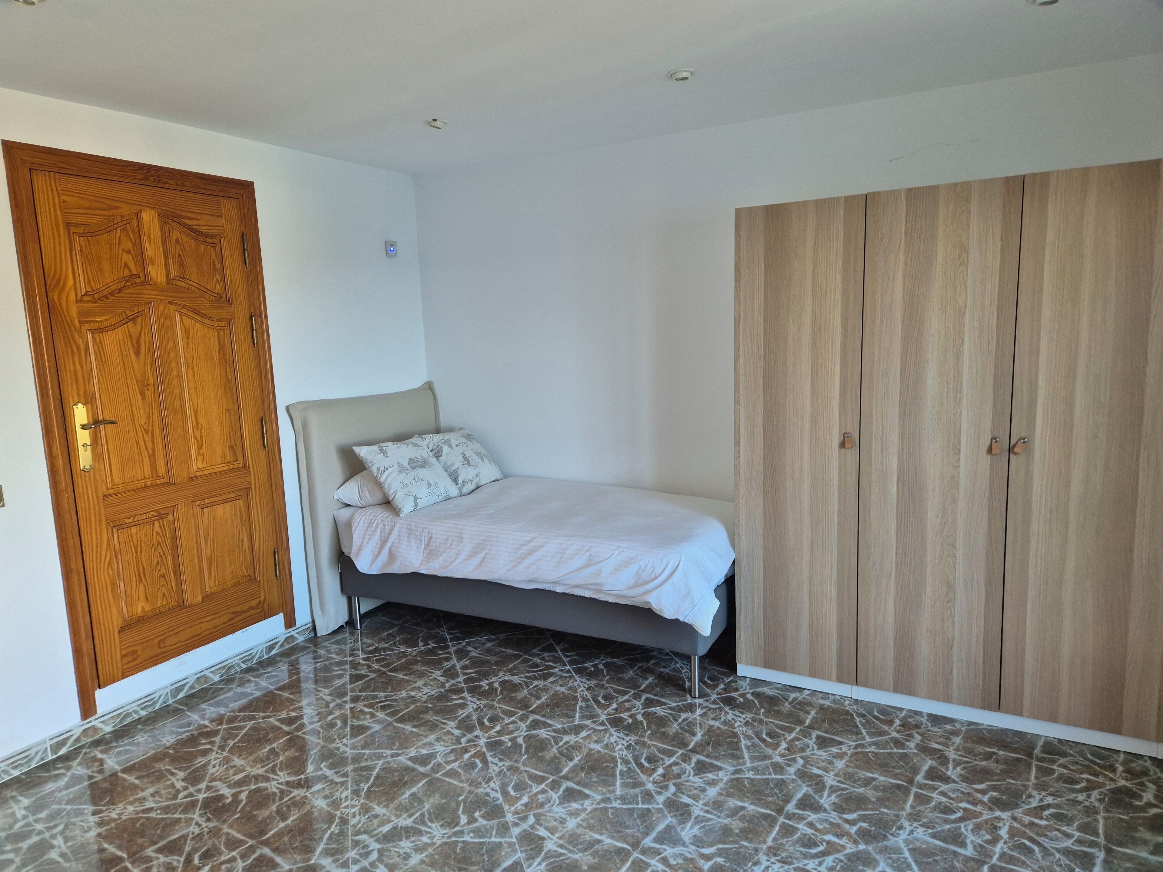 Quarto com cama, guarda-roupa e porta de madeira.