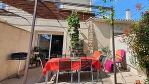 Ein überdachter Patio-Bereich mit Tisch und Stühlen, einer Pergola und einer Steinmauer.