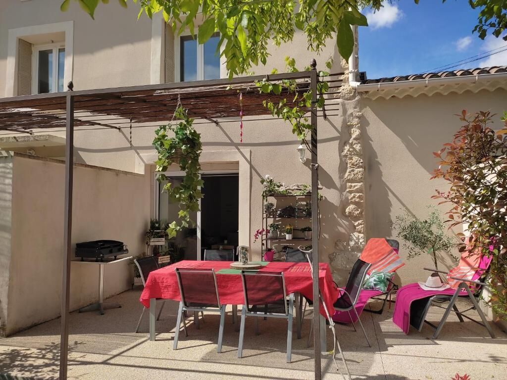 An outdoor patio with a table and chairs, a pergola, and potted plants.