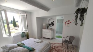 Ein Schlafzimmer mit Bett, Schminktisch, Stuhl und großem Fenster.