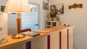 Una reception con una lampada, un quadro incorniciato e un vaso con fiori.
