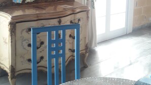 Une pièce avec une commode de style vintage, une chaise bleue et un grand miroir.