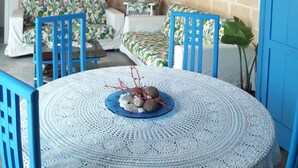 Une pièce chaleureuse avec une table ronde, des chaises bleues, un canapé à motifs et un mur en briques.
