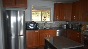 Una cucina moderna con elettrodomestici in acciaio inox, pensili in legno e una finestra vista verde.