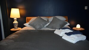Un letto rifatto con cuscini, una lampada e una candela su un comodino.