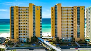 Un hôtel de grande hauteur doté de nombreux balcons, offrant une vue sur la plage et disposant d’un parking.