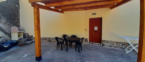 A covered patio with a table and chairs, a door, and a small outdoor kitchen area.