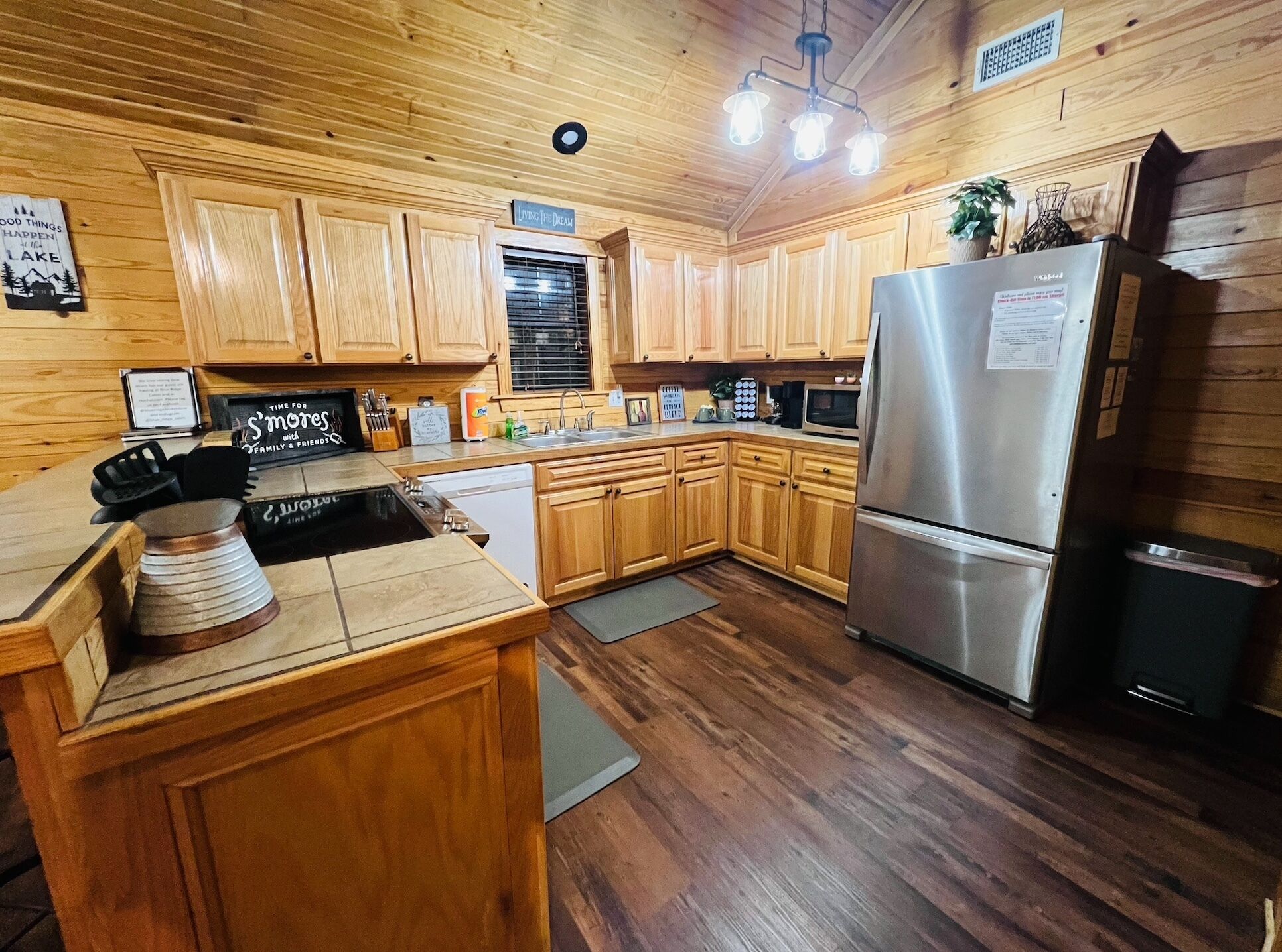 A kitchen with wooden cabinets, a stainless steel refrigerator, a stove, and a sink.