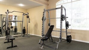 Un gimnasio con diversos equipos de ejercicio, como una banca, una estructura para sentadillas y una banca de pesas.