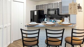 Una cocina moderna con una isla central, electrodomésticos negros y taburetes de bar.