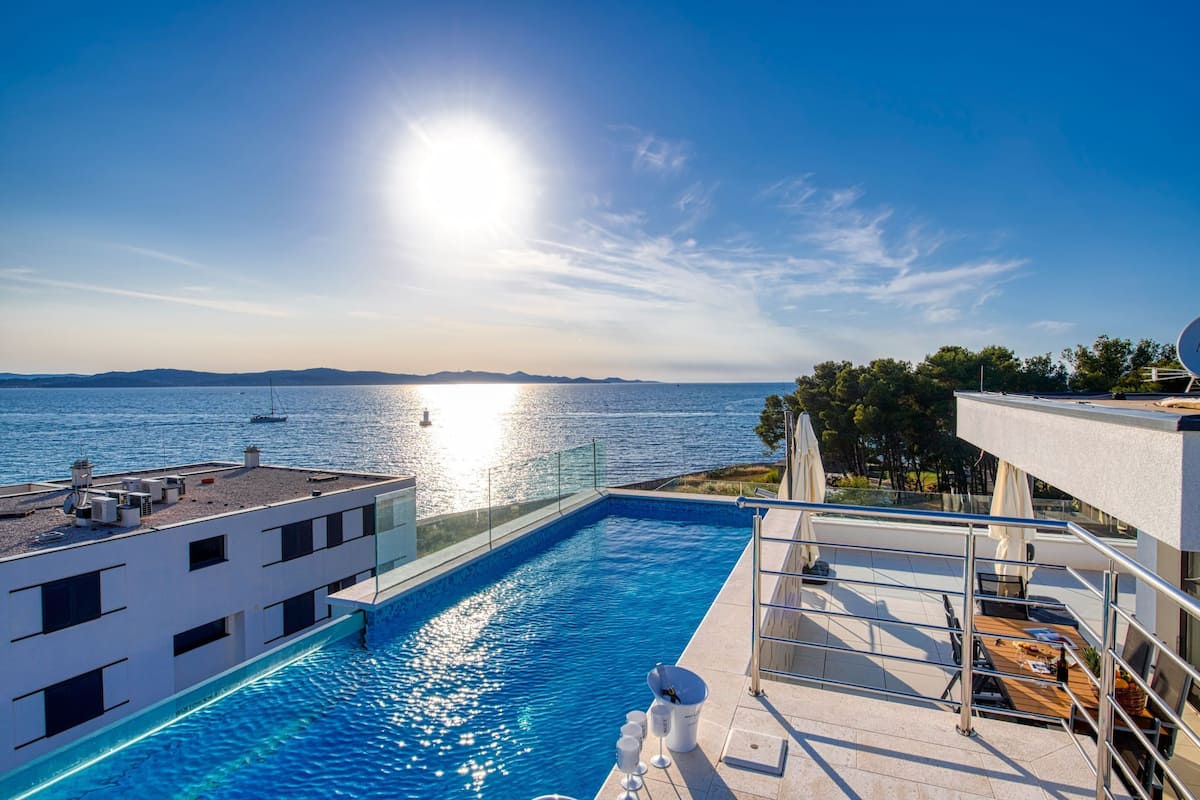 A modern building with a rooftop pool overlooking a body of water.