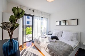 Relax in a serene space with a large bed, bedside table, and sliding glass door to an outdoor area.