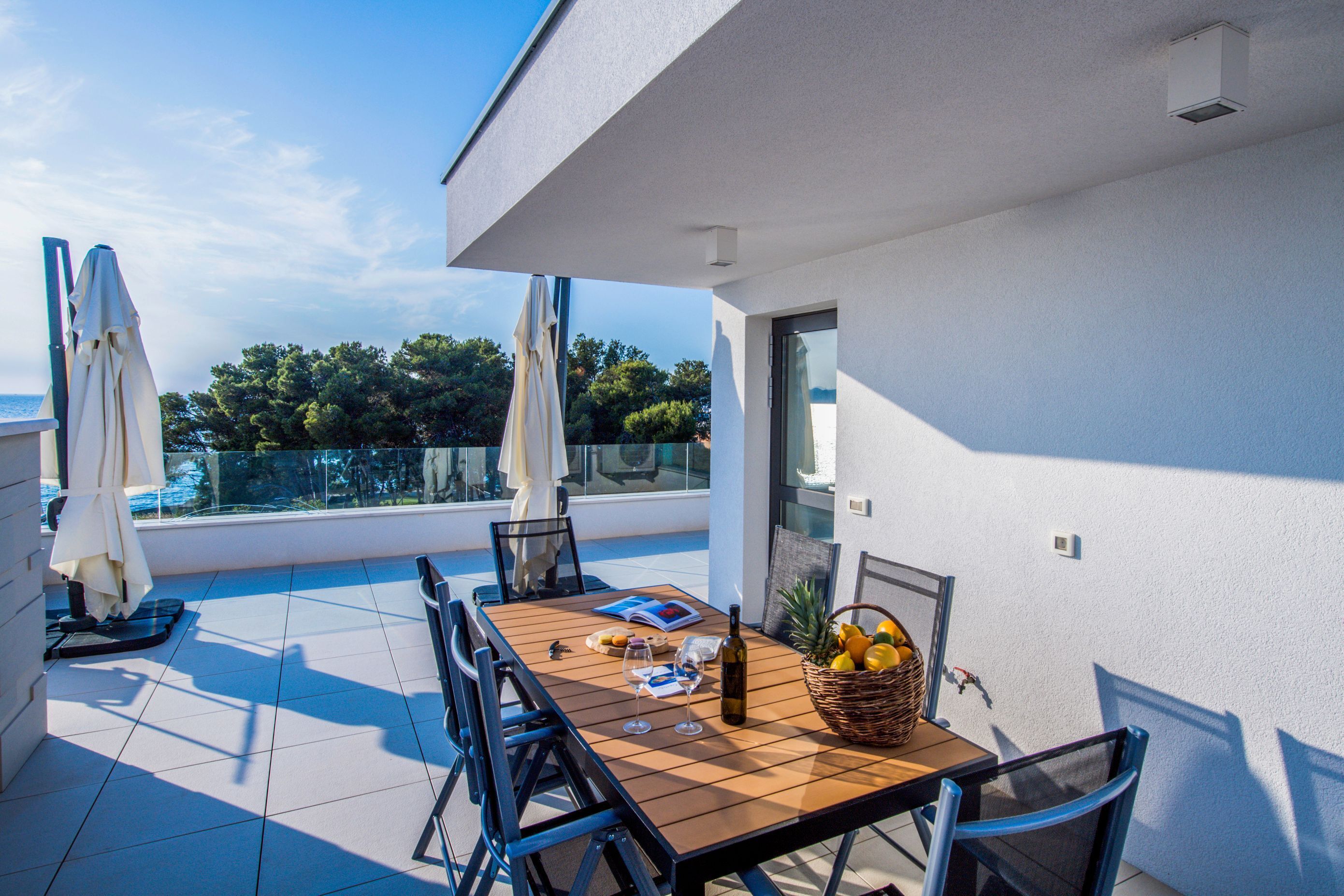 Une terrasse avec une table dressée pour le repas, des chaises d’extérieur et des parasols.