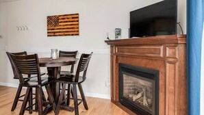 Ein Essbereich mit einem runden Tisch, Stühlen, einem Kamin, einem Fernseher und einer an der Wand befestigten amerikanischen Flagge.