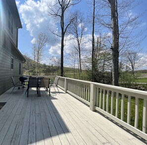 A wooden deck with a white railing, a barbecue grill, and outdoor furniture.