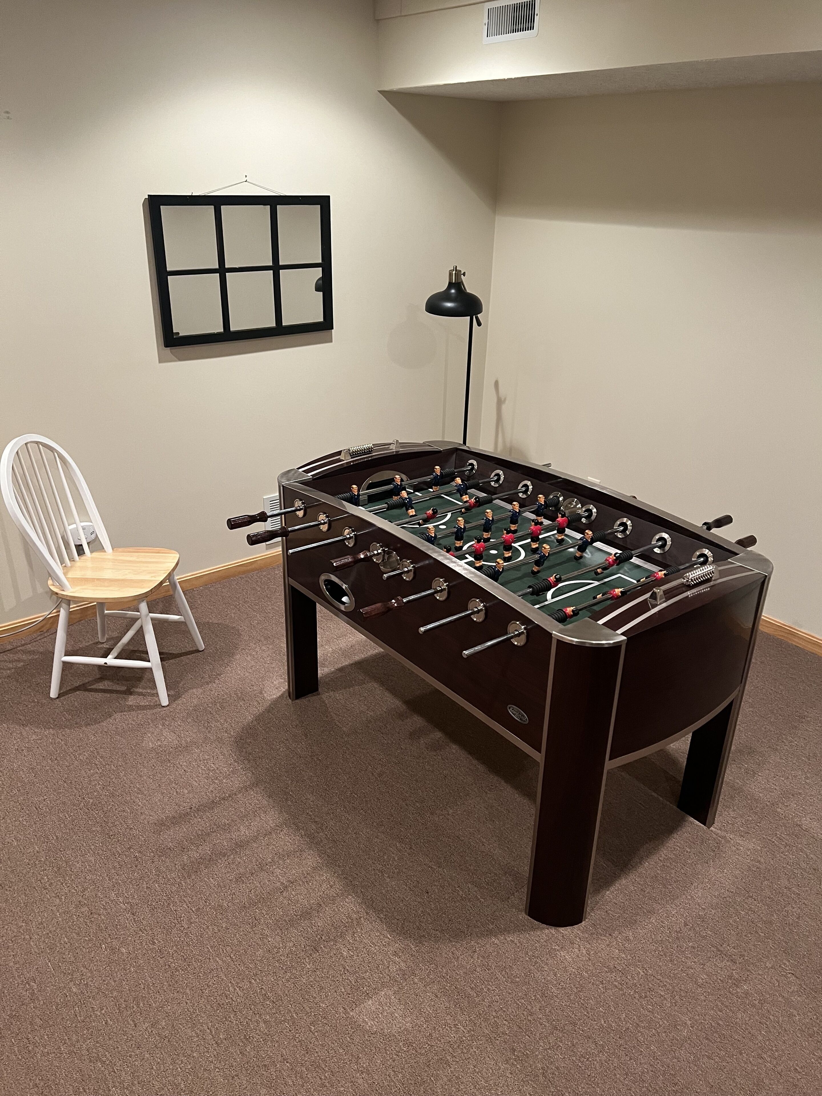 Une pièce avec une table de baby-foot, une chaise et une lampe.