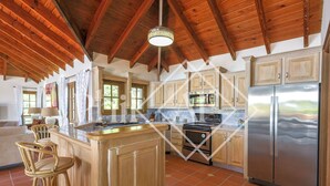 A spacious kitchen with wooden cabinets, a large island with stools, a stainless steel refrigerator, and a wooden ceiling. - Beautiful 5 bed-rooms Villa at Terres Basses (Saint Martin)