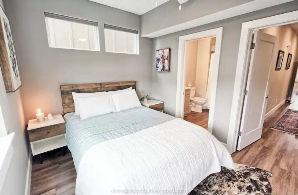 A bedroom with a large bed, bedside tables, a wooden headboard, and a dog on the floor.