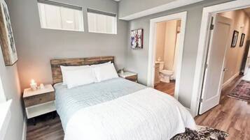 A bedroom with a large bed, bedside tables, a wooden headboard, and a dog on the floor.