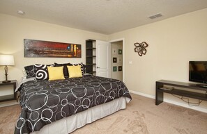 A bedroom with a large bed, a TV, a painting, and a door leading to another room. - Moderno Townhouse 4 hab· Piscina · Resort con Cine & Tobogán, 8 millas de Disney (Kissimmee)