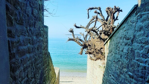 En smal stenlagd gång som leder till en strand med fri utsikt över havet.