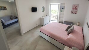 A bedroom with a bed, a bedside table, a TV, a mirror, and a sliding door leading to a balcony. - Nice apartment not far from the sea (Lacco Ameno)