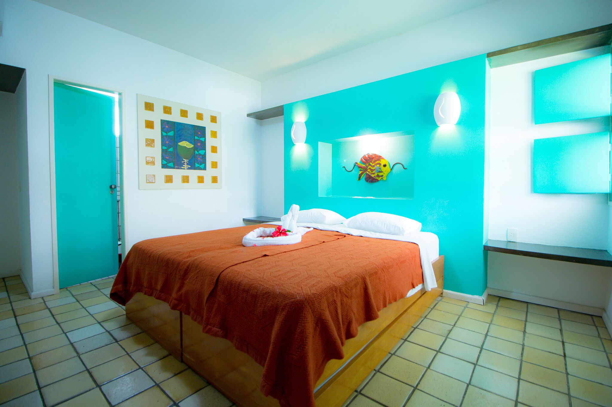 A hotel room with a bed, a wall-mounted artwork, and a bathroom door.