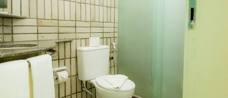 A small, tiled bathroom with a toilet, sink, and a trash can.