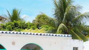 A poolside area with white lounge chairs, a clear blue pool, and a white building with turquoise windows. - Pousadar Marahú (Ipojuca)