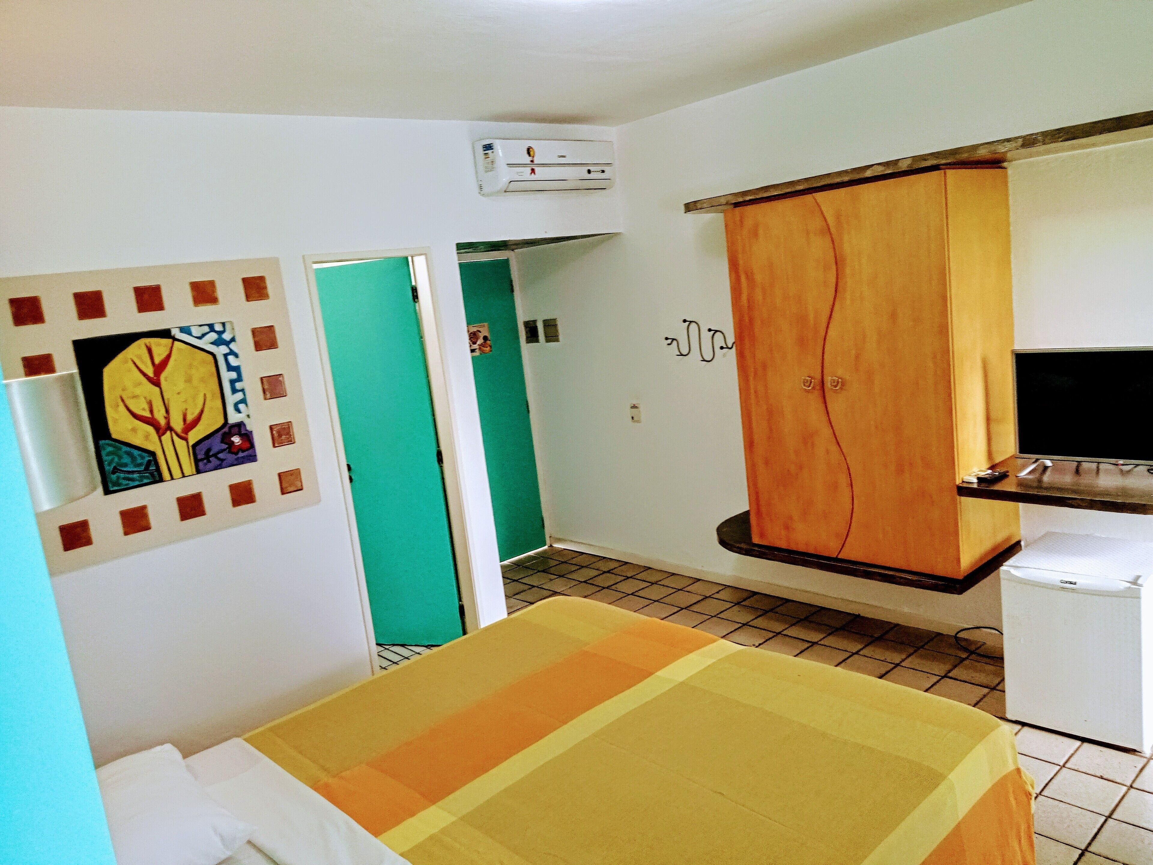 A room with a bed, a wardrobe, a television, and a refrigerator.