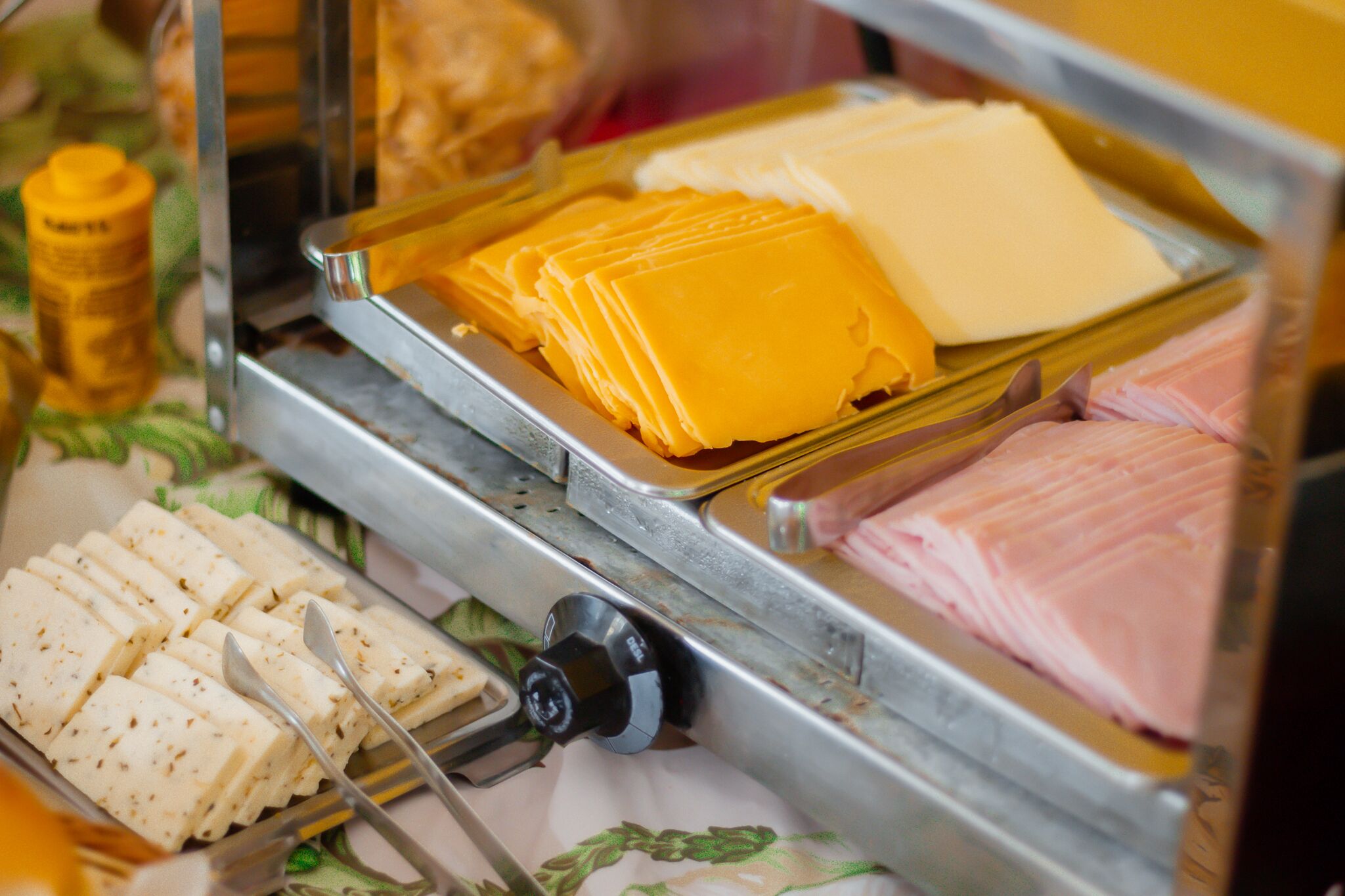 Un présentoir de fromages et de charcuteries avec un plateau en métal et un bouton noir.