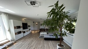 A modern living room with a large sofa, a television, and a potted plant.