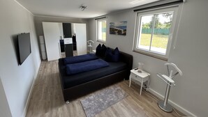 A modern bedroom with a large bed, bedside tables, a TV, and a window with a view of the outdoors.