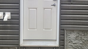 Une porte d’entrée blanche avec un trou de serrure et un sonnette.