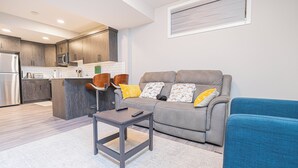 Un salon moderne avec un canapé gris, une petite table et un fauteuil bleu.