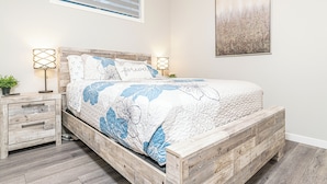Une chambre à coucher avec un lit en bois, une table de chevet avec des tiroirs, une lampe et un tableau accroché au mur.