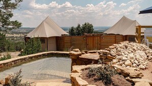 Deux tentes coniques, avec une piscine et une terrasse en bois au premier plan.