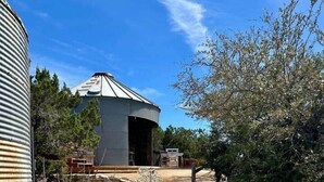 Un chemin menant à un bâtiment doté d’un toit en métal et dont la porte est ouverte vers l’intérieur.