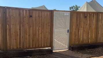 Enter a serene courtyard through the charming gate, surrounded by a natural setting.