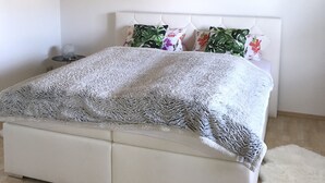 Een slaapkamer met een bed, een wit hoofdbord en een plafond met houten balken.